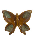 Butterfly-shaped ceramic ornament with brown and green colors on a white background
