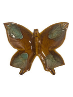 Butterfly-shaped ceramic ornament with brown and green colors on a white background
