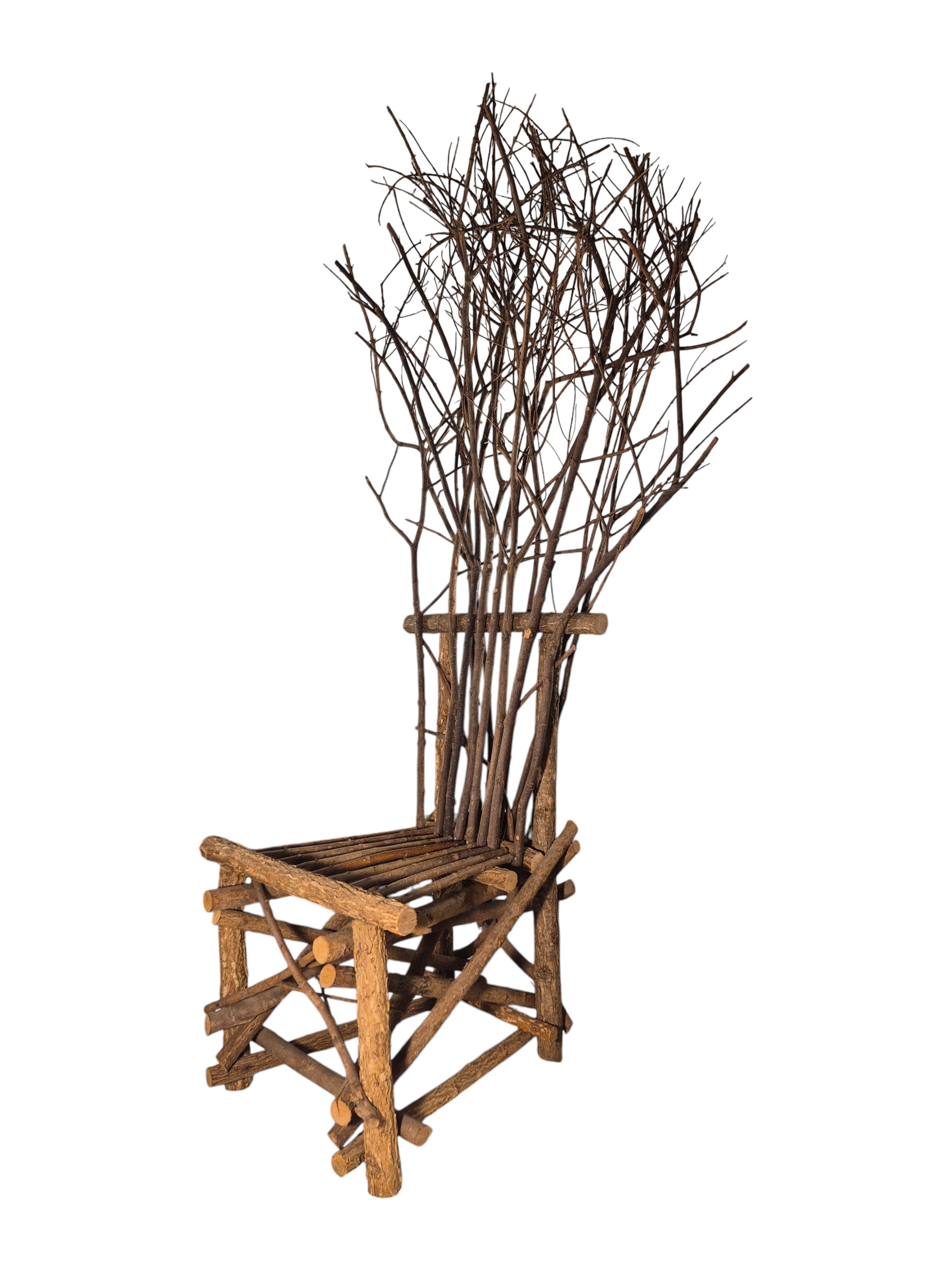 Vintage, handmade rustic twig chair in a left-front view featuring tall, branching backrest, slatted branch seat, and cross-braced legs. Made from raw branches with unpeeled bark. Sold vintage as-is in very good condition.