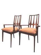 Mid Century Modern Broyhill Brasilia walnut arm dining chair displayed two side by side. Features a signature cathedral slatted back and original beige geometric upholstered seat. Vintage as-is, gently refreshed, as part of a set of six.