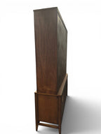 Mid Century Modern Broyhill Brasilia walnut breakfront China cabinet in a right-back view. Features the Brasilia collection's catseye sweeping arches and tapered legs, with brass hardware and glass display doors. Vintage as-is, gently refreshed, including credenza base with three drawers and two doors and top display deck with two doors.