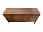 Mid Century Modern Broyhill Brasilia walnut base credenza, the lower half of the breakfront China cabinet set, in a front view. Features the Brasilia collection's catseye sweeping arches, tapered legs, and brass hardware. Vintage as-is, gently refreshed, as a pair with top display deck.