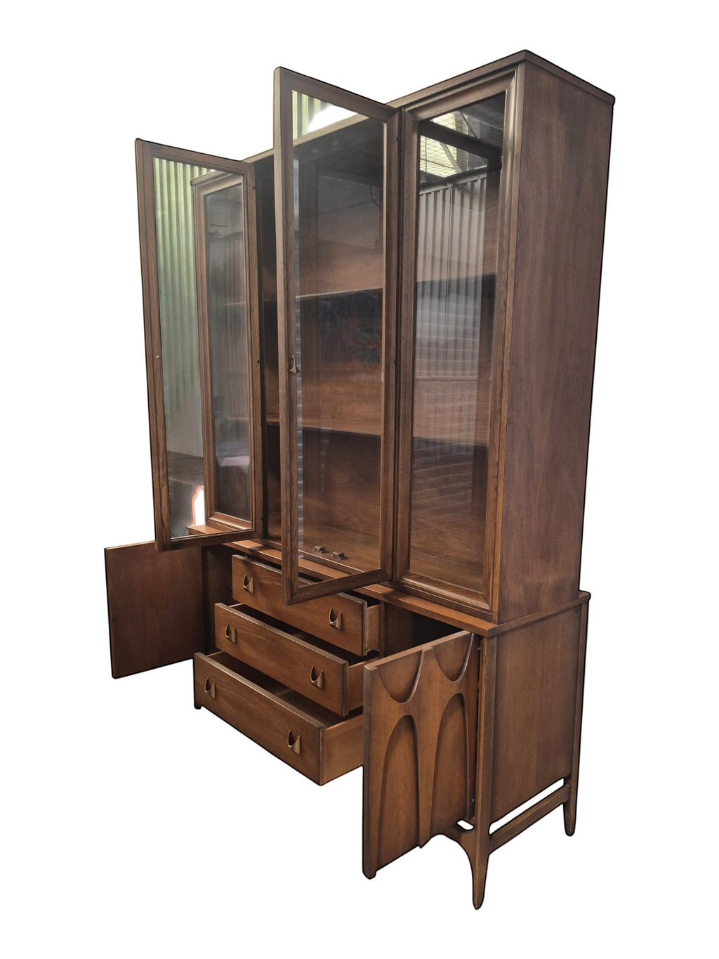 Mid Century Modern Broyhill Brasilia walnut breakfront China cabinet in a left-front view, with open doors and drawers. Features the Brasilia collection's catseye sweeping arches and tapered legs, with brass hardware and glass display doors. Vintage as-is, gently refreshed, including credenza base with three drawers and two doors and top display deck with two doors.