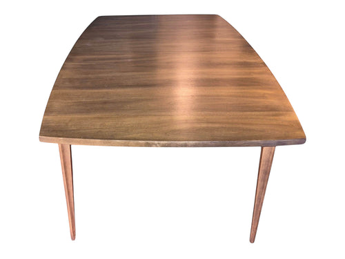Mid Century Modern Broyhill Brasilia walnut dining table in a front view. Features the Brasilia collection's signature tapered legs and bow-sided rectangle table top. Vintage as-is, gently refreshed, including three interior leaves.