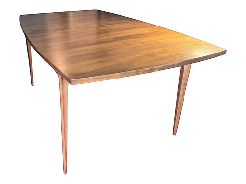 Mid Century Modern Broyhill Brasilia walnut dining table in a front-right angle view. Features the Brasilia collection's signature tapered legs and bow-sided rectangle table top. Vintage as-is, gently refreshed, including three interior leaves.