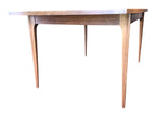Mid Century Modern Broyhill Brasilia walnut dining table in a low front view. Features the Brasilia collection's signature tapered legs and bow-sided rectangle table top. Sold as-is, gently refreshed, including three interior leaves.