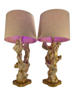 Vintage 1950s mid-century modern sculptural table lamp made of chalkware plaster, shaped like twisted biomorphic driftwood featuring a white gesso finish with hand-painted gold leaf highlights, sitting on a scalloped gold base against a white backdrop.