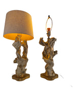 Vintage 1950s mid-century modern sculptural table lamp made of chalkware plaster, shaped like twisted biomorphic driftwood featuring a white gesso finish with hand-painted gold leaf highlights, sitting on a scalloped gold base against a white backdrop.