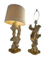 Vintage 1950s mid-century modern sculptural table lamp made of chalkware plaster, shaped like twisted biomorphic driftwood featuring a white gesso finish with hand-painted gold leaf highlights, sitting on a scalloped gold base against a white backdrop.