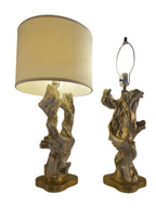Vintage 1950s mid-century modern sculptural table lamp made of chalkware plaster, shaped like twisted biomorphic driftwood featuring a white gesso finish with hand-painted gold leaf highlights, sitting on a scalloped gold base against a white backdrop.
