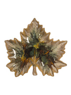 Curated Vintage Design leaf-shaped ceramic dish with a multi-tonal green, brown, and yellow marbled glaze.